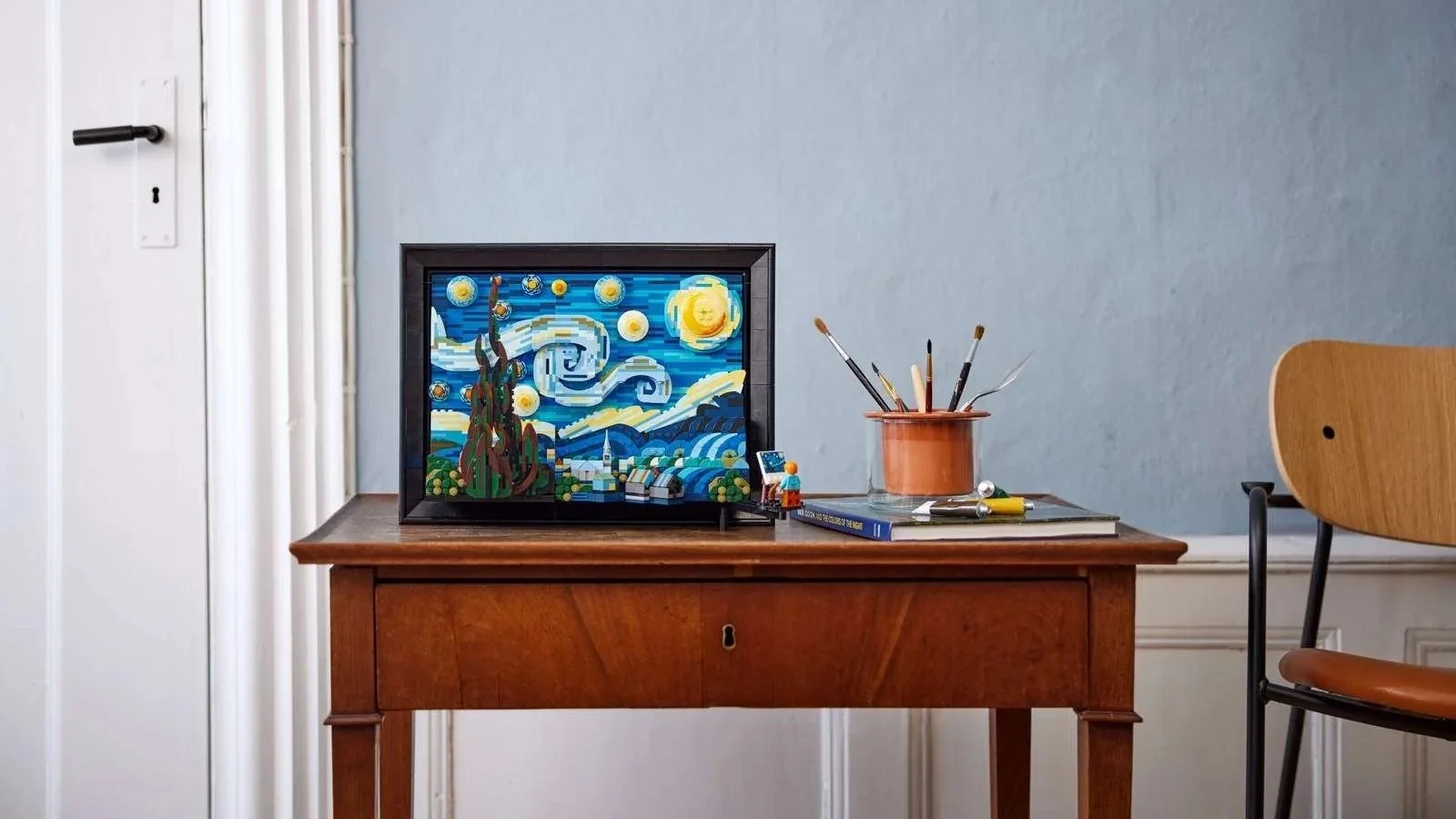 LEGO Vincent van Gogh The Starry Night set on a vintage writing desk beside a jar of paintbrushes