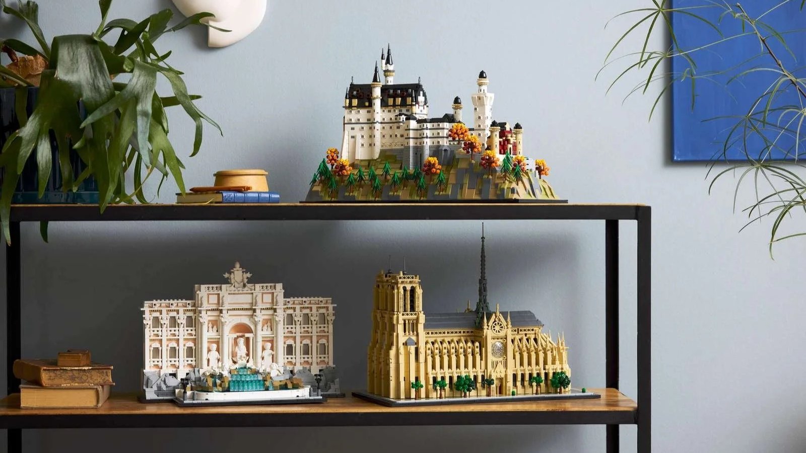 Three LEGO Architecture sets styled on black metal shelves: Neuschwanstein Castle, Trevi Fountain, and Notre-Dame de Paris