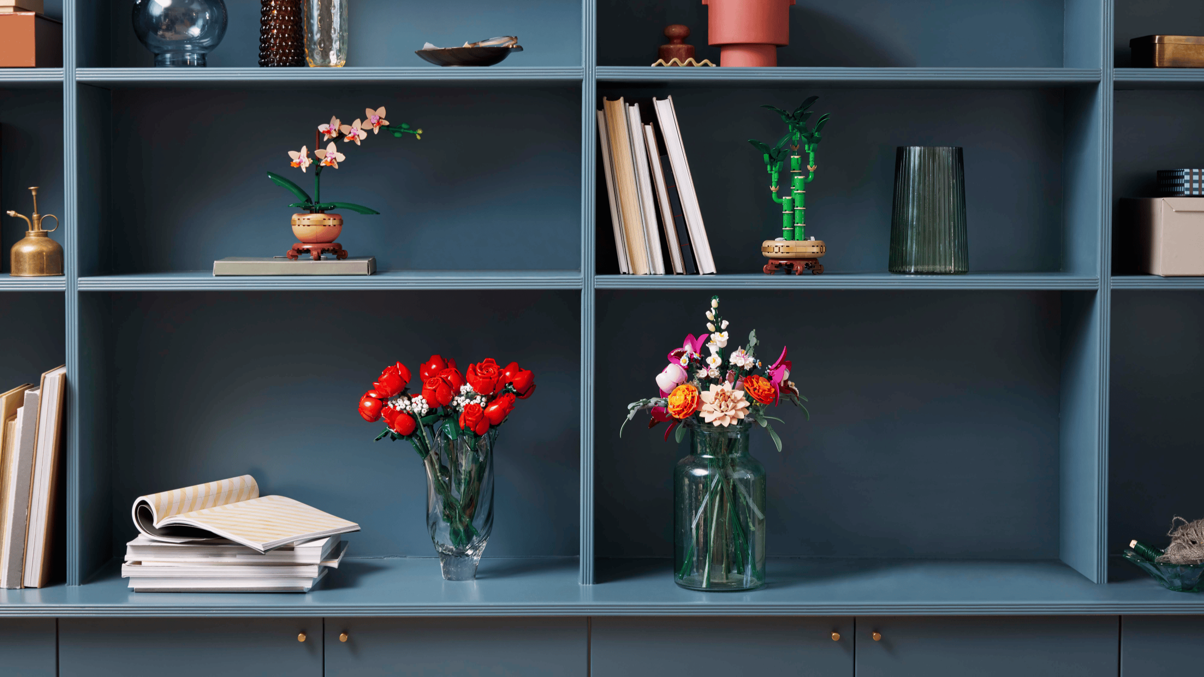 Collection of LEGO Botanical sets including an orchid, bamboo, and flower bouquets on a built-in shelving unit