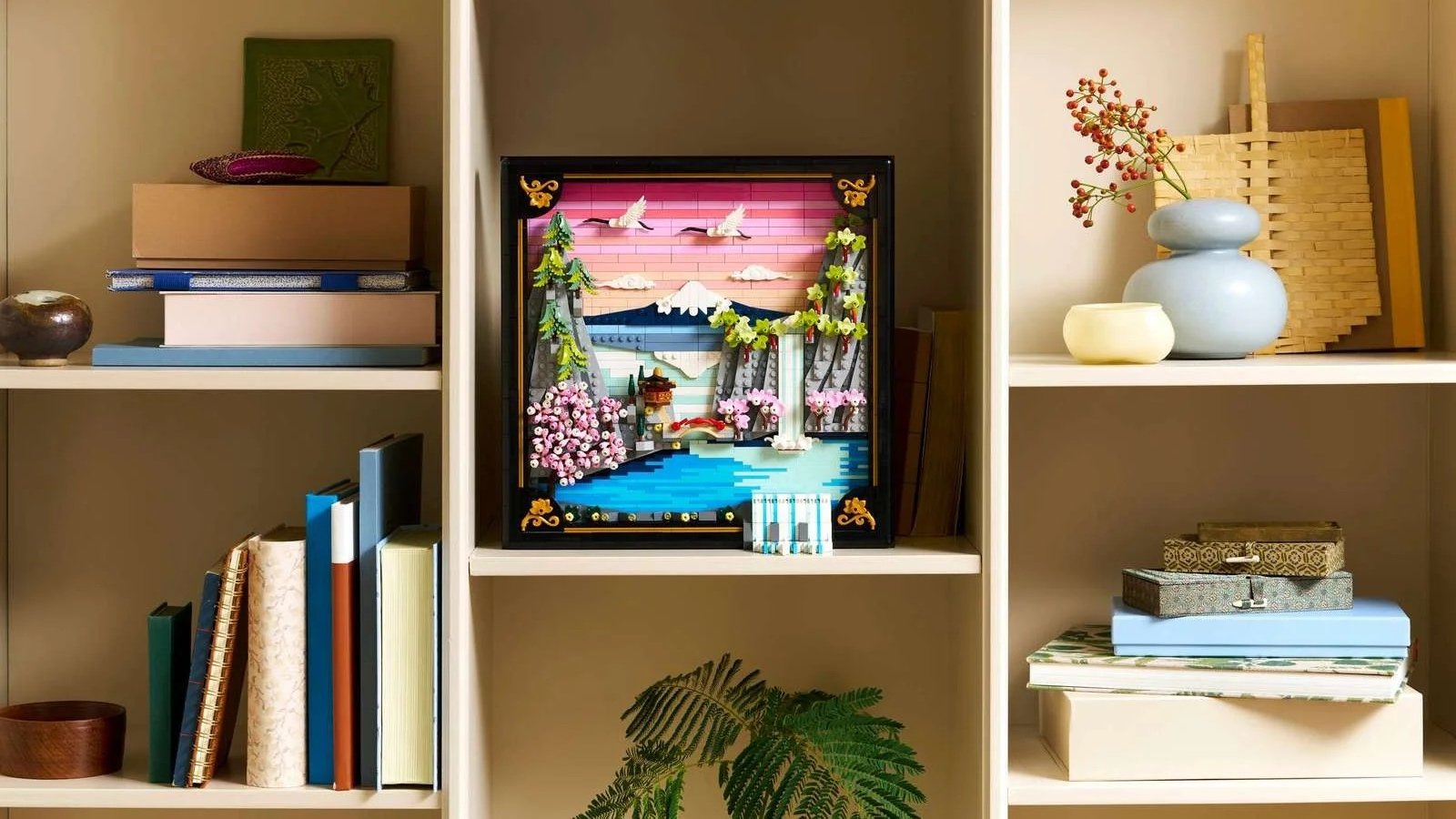 LEGO Japanese Cherry Blossom Landscape wall art displayed on a bookshelf, showing Mount Fuji, blossoming trees, and cranes in flight