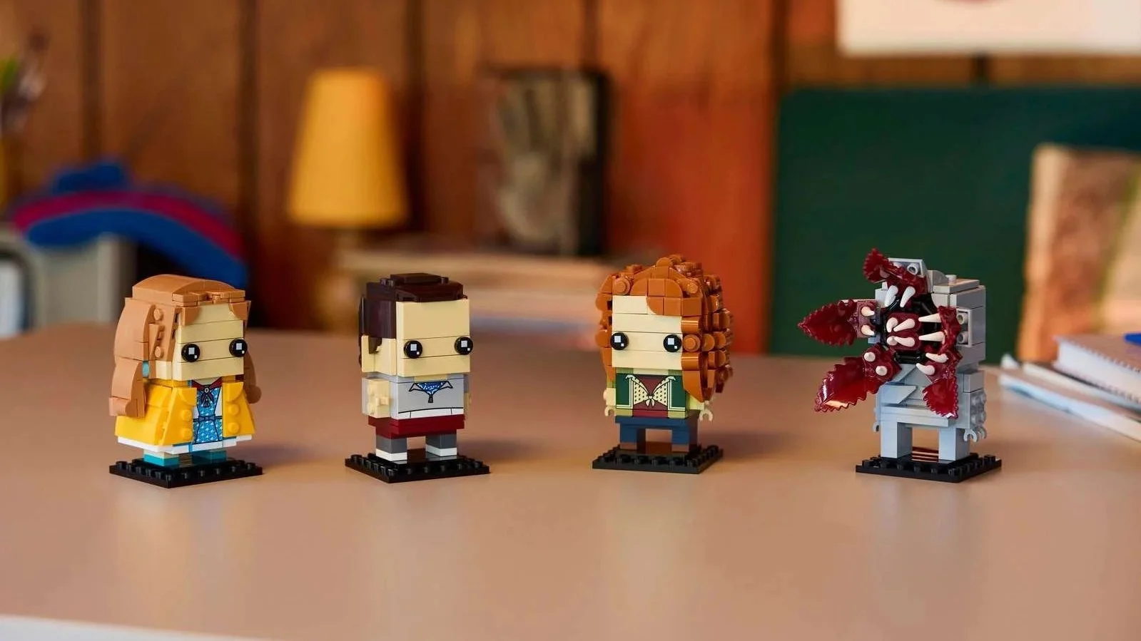 LEGO Stranger Things figures of Eleven, Max, Demogorgon and Holly standing on black display bases on a tabletop