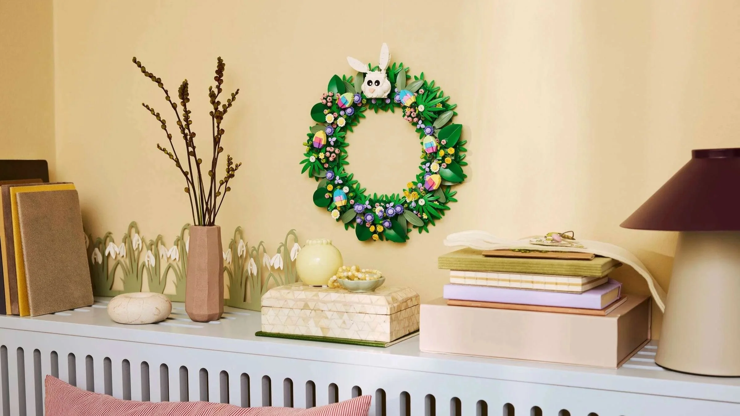 LEGO Spring Wreath set with pastel flowers, patterned eggs, and a white bunny, hanging on a pale yellow wall