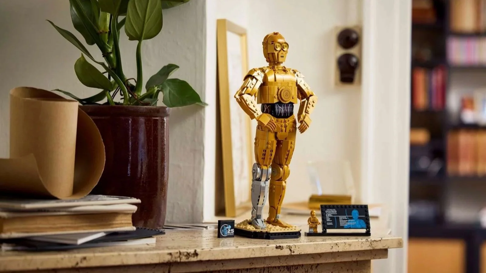 LEGO Star Wars C-3PO displayed on a marble mantel beside a potted plant and a roll of craft paper