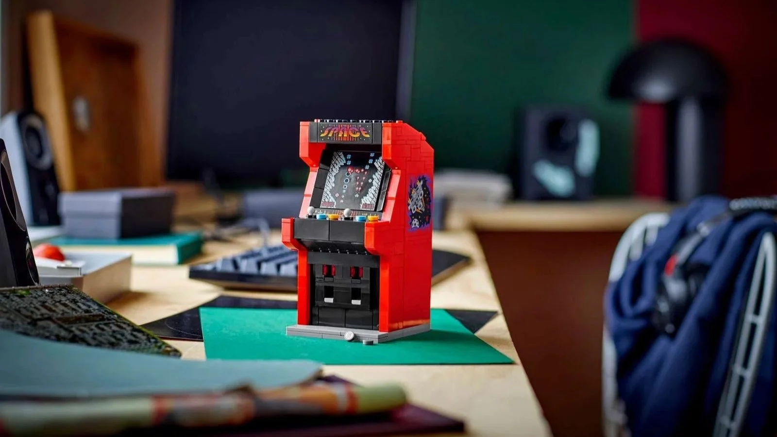 LEGO Arcade Machine set in red with a space-themed marquee, staged on a desk next to a keyboard and monitor