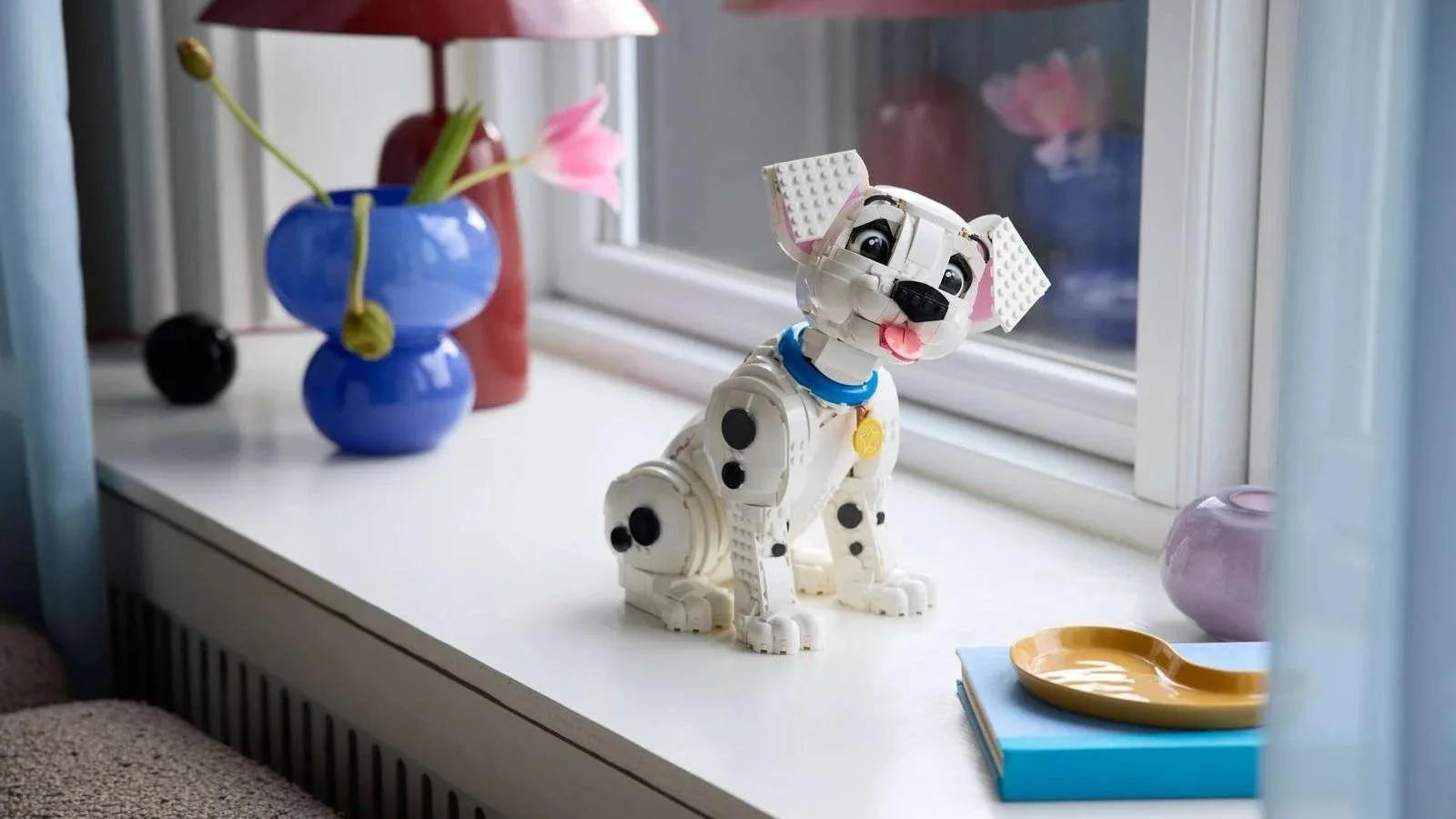 LEGO 101 Dalmatians Puppy set sitting on a white windowsill beside a pink tulip in a blue glass vase
