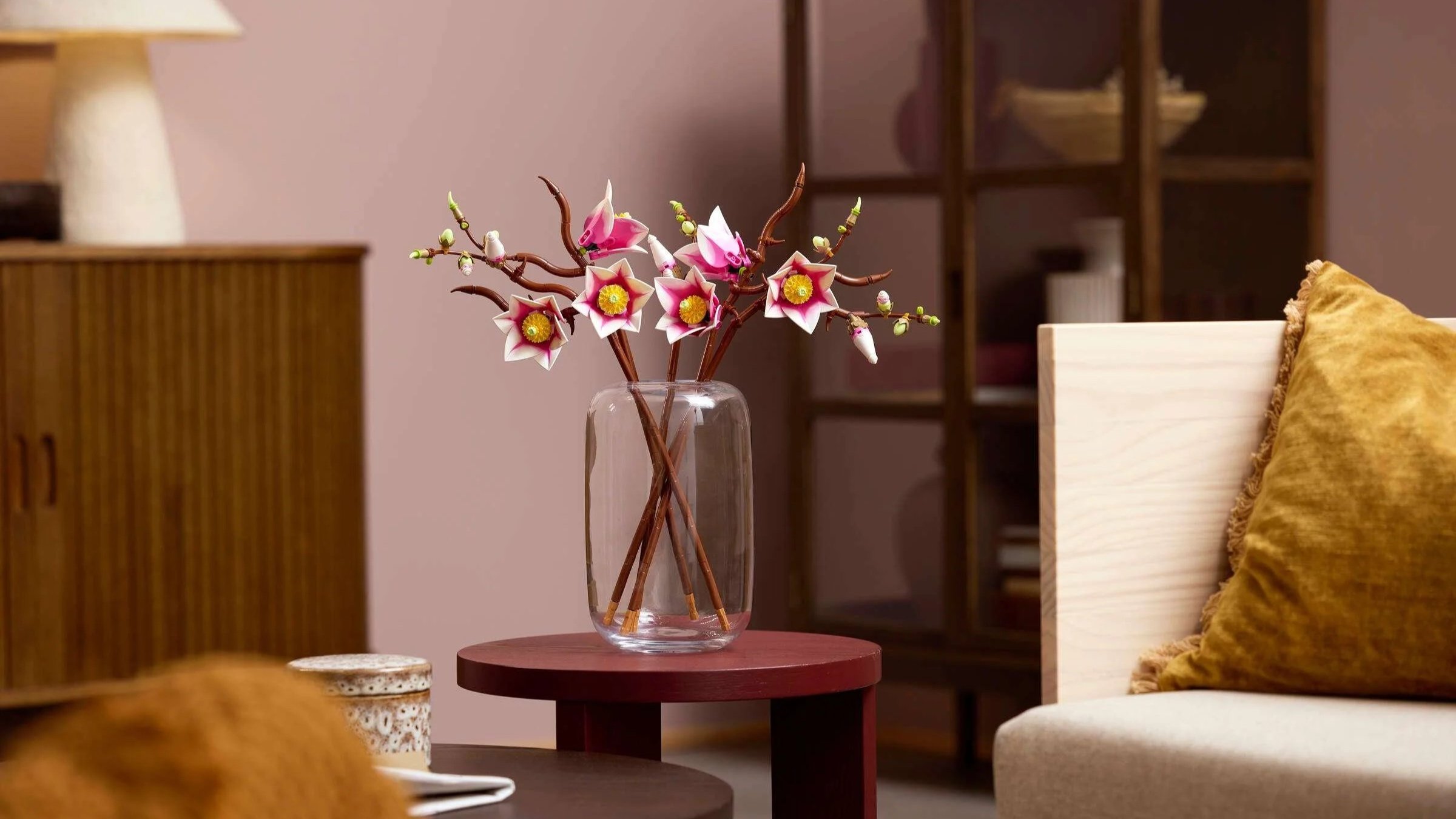LEGO Magnolia Branches in a clear vase on a burgundy side table beside a cream armchair