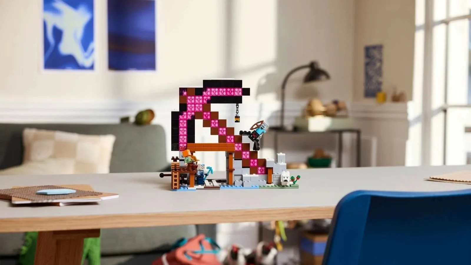 LEGO Minecraft The Pickaxe Mine set on a desk in a bright living room, showing the pink ore mine, hanging pickaxe, mining minifigures, and mob figures