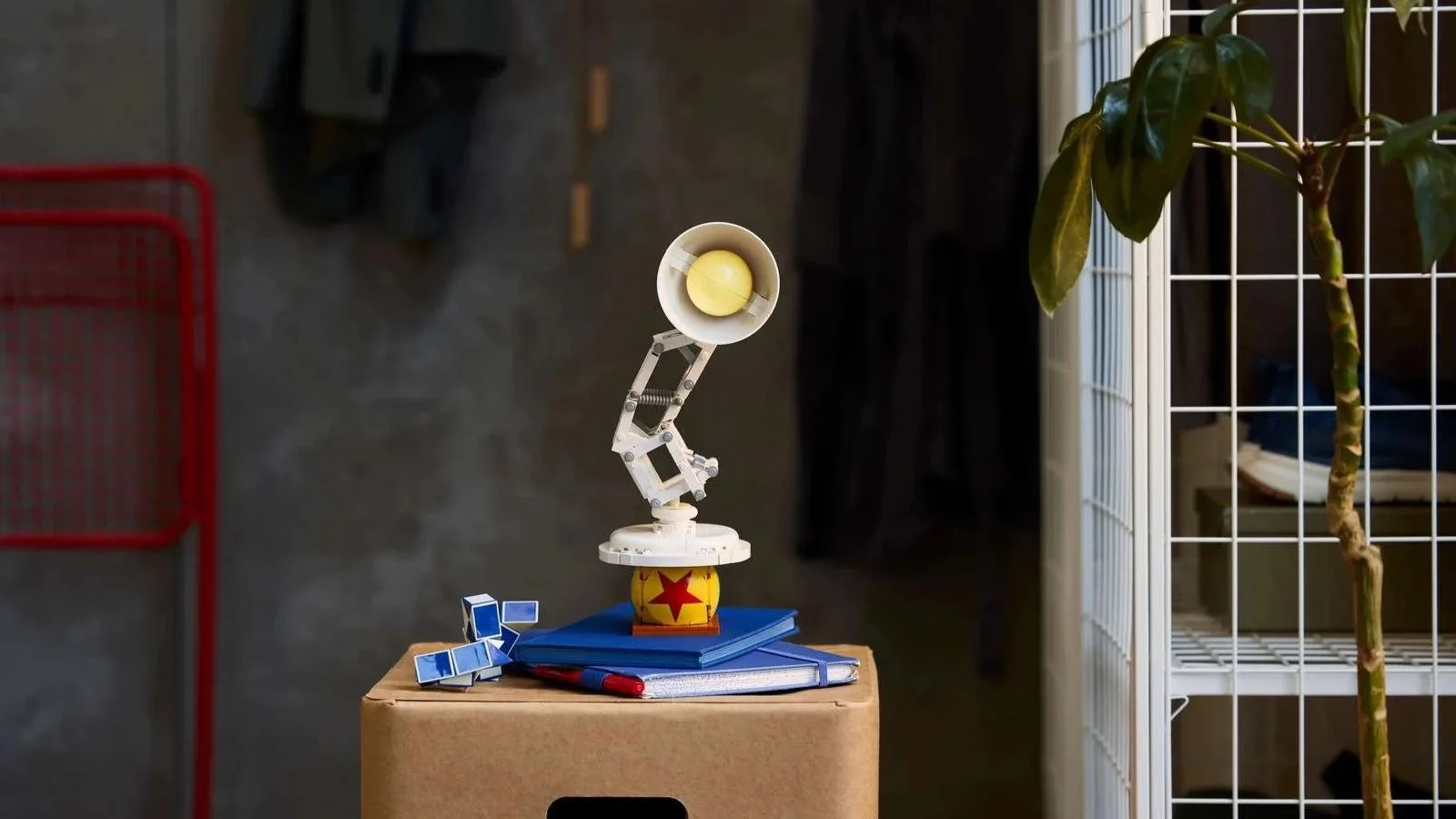 LEGO Disney Pixar Luxo Jr. lamp set perched on blue notebooks atop a cardboard storage box