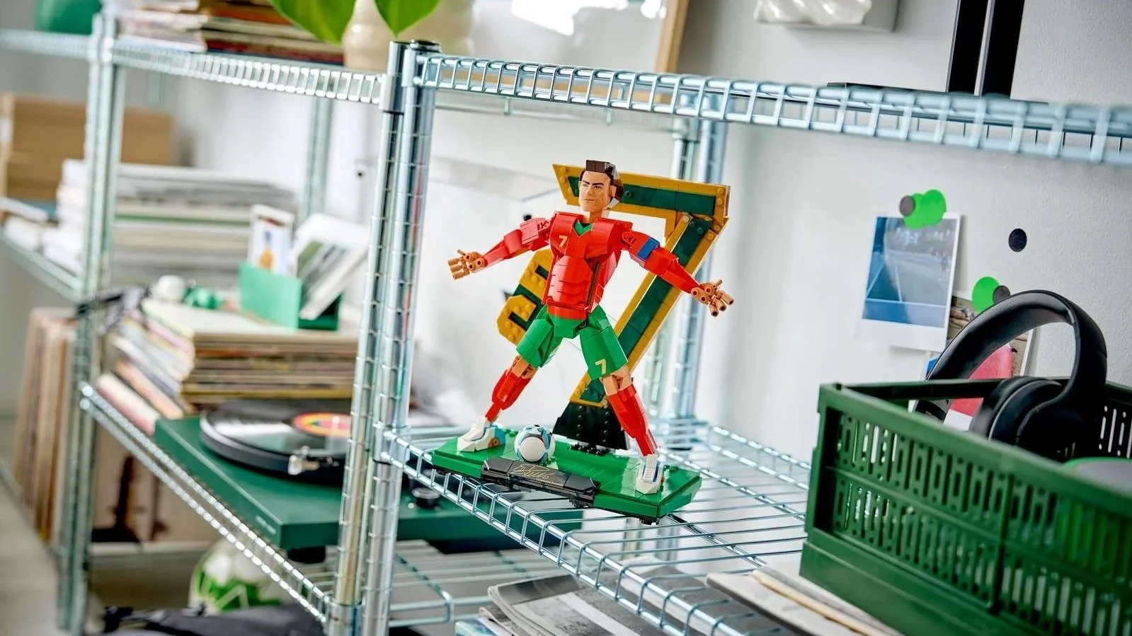 LEGO Cristiano Ronaldo Soccer Legend set in his signature pose, wearing a red and green kit, on a metal shelf with records and headphones