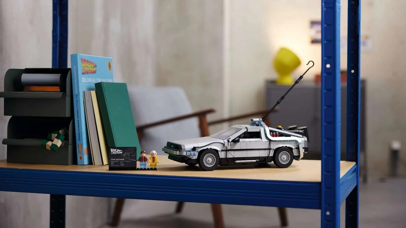 LEGO Back to the Future Time Machine set displayed on a blue shelving unit beside books and the Marty and Doc minifigures.