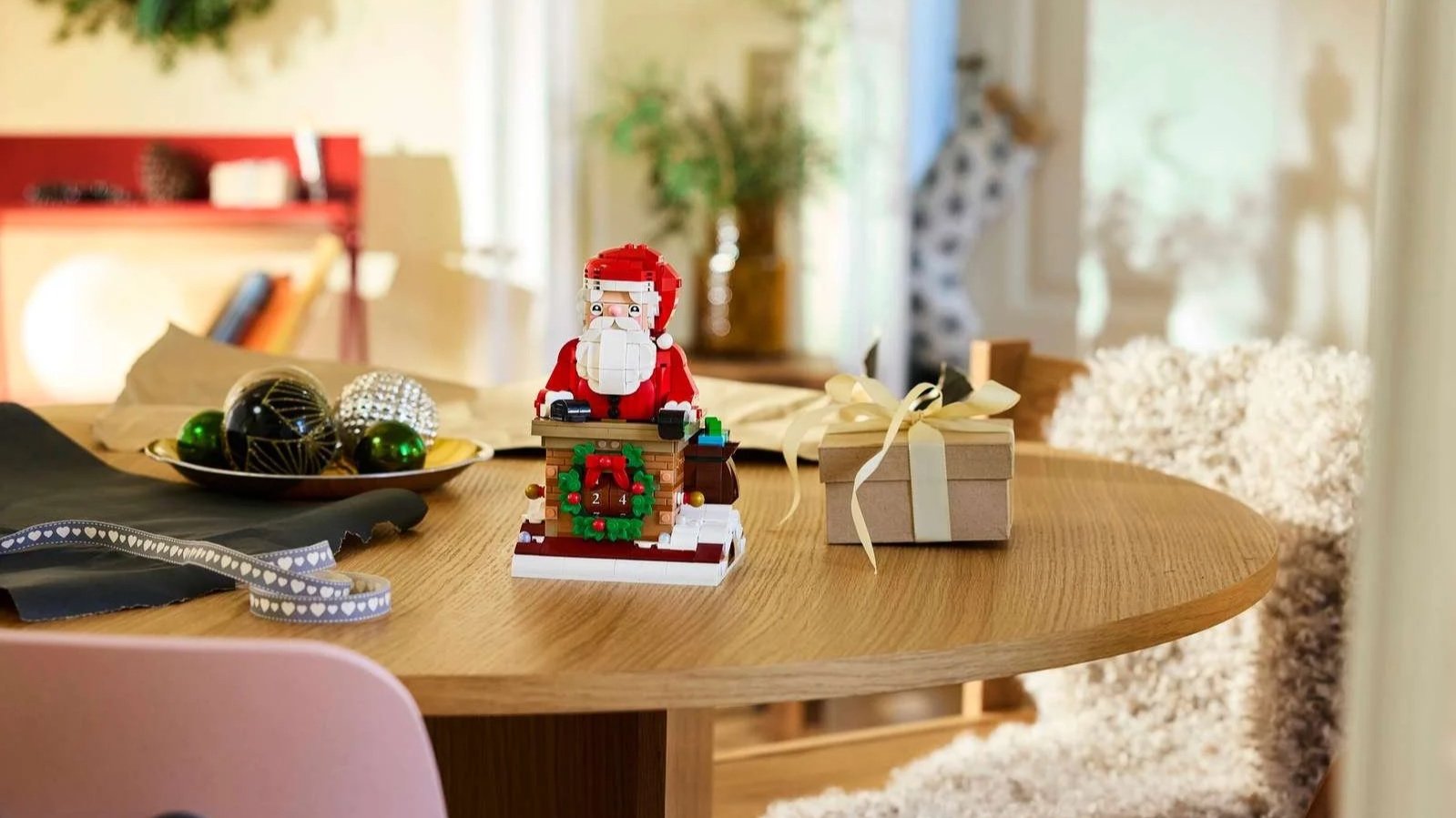 LEGO Santa’s Holiday Countdown set with Santa behind a brick chimney and number-dial wreath, styled on a wooden table with a wrapped gift