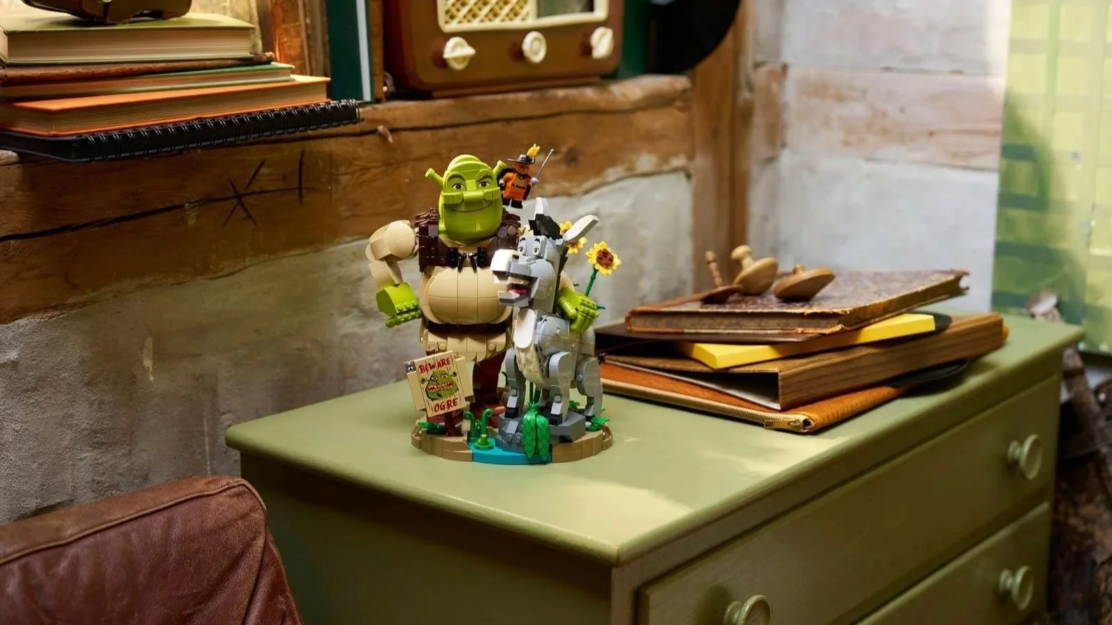 LEGO Shrek, Donkey and Puss in Boots set standing on a green dresser in a rustic cottage room