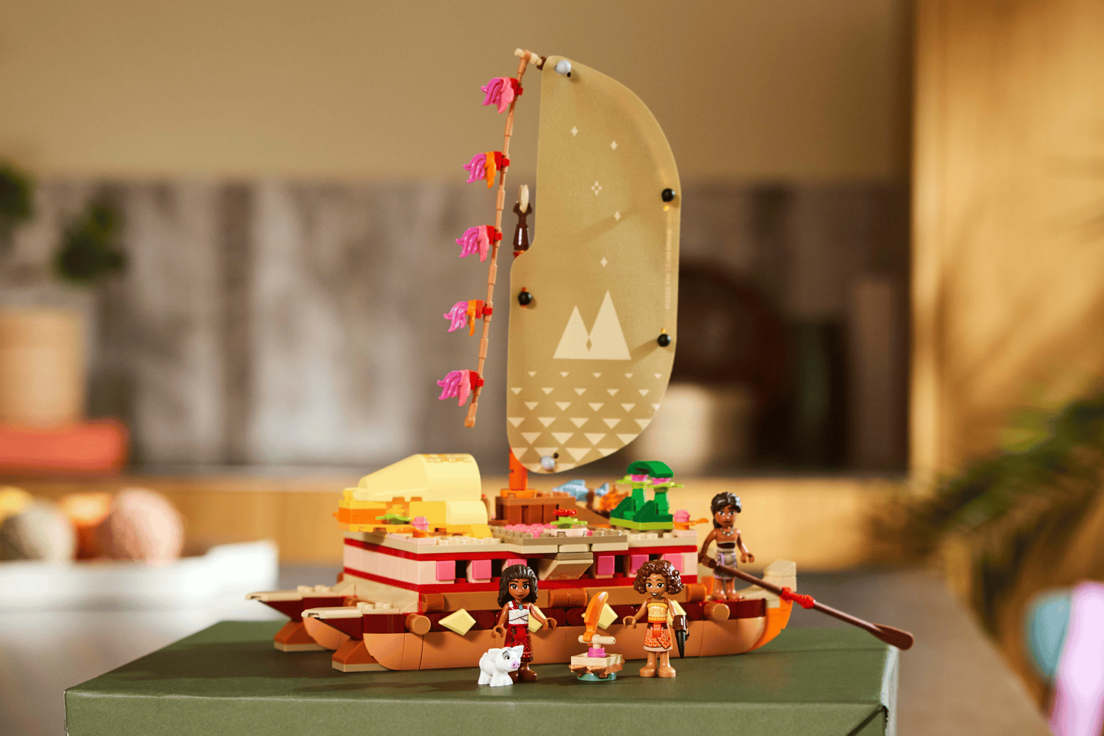 LEGO Moana's Adventure Canoe set on a green box, a catamaran with a tan sail, pink feather streamers, three figures and a small white pig