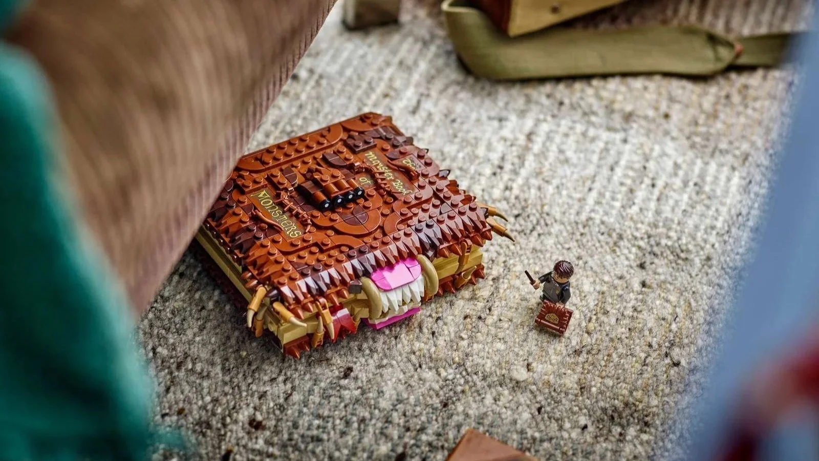 LEGO Chomping Monster Book of Monsters set baring its teeth on a carpeted floor beside a tiny Neville Longbottom minifigure