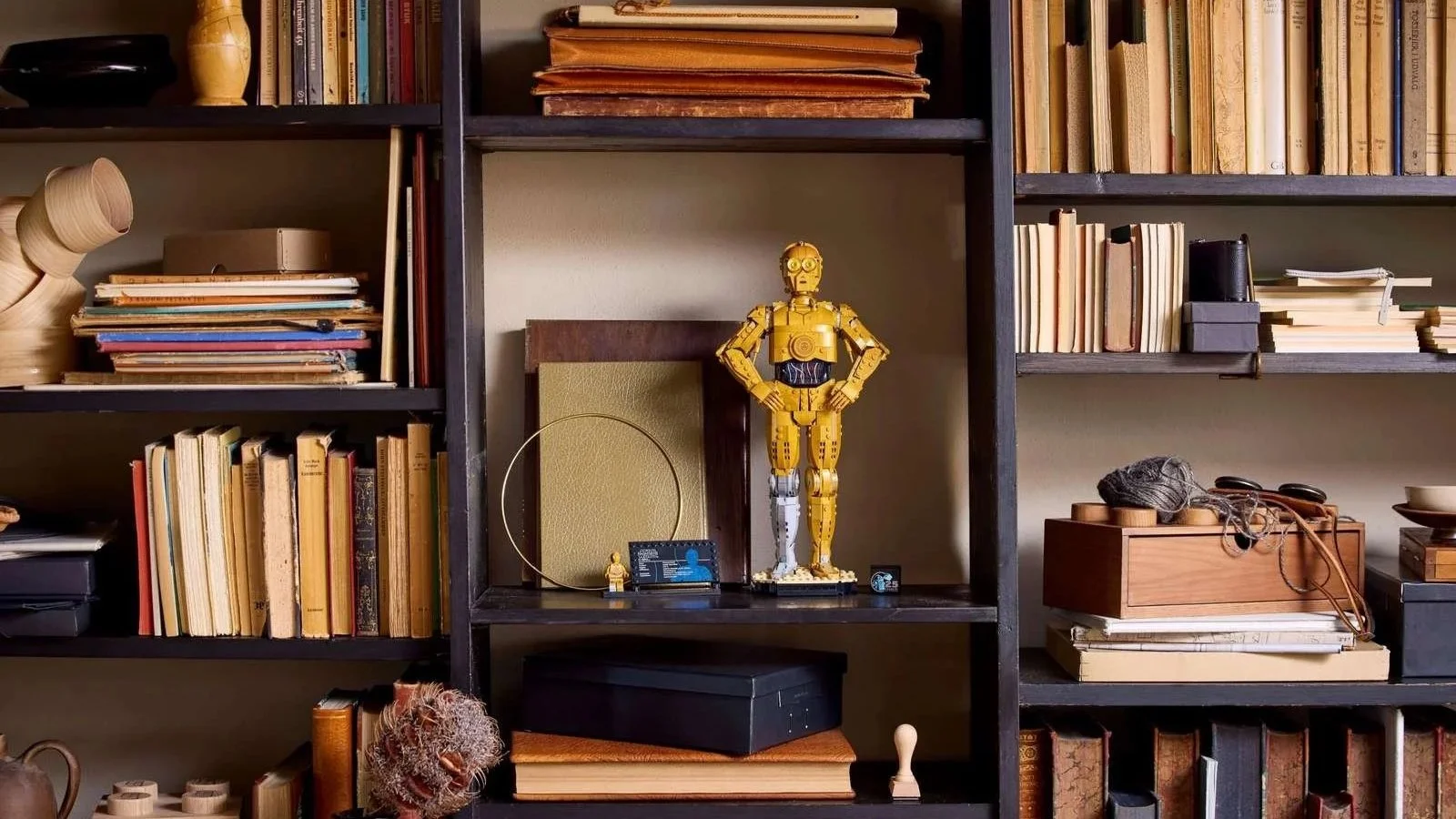 LEGO Star Wars C-3PO standing hands on hips on a dark bookshelf among rows of vintage books