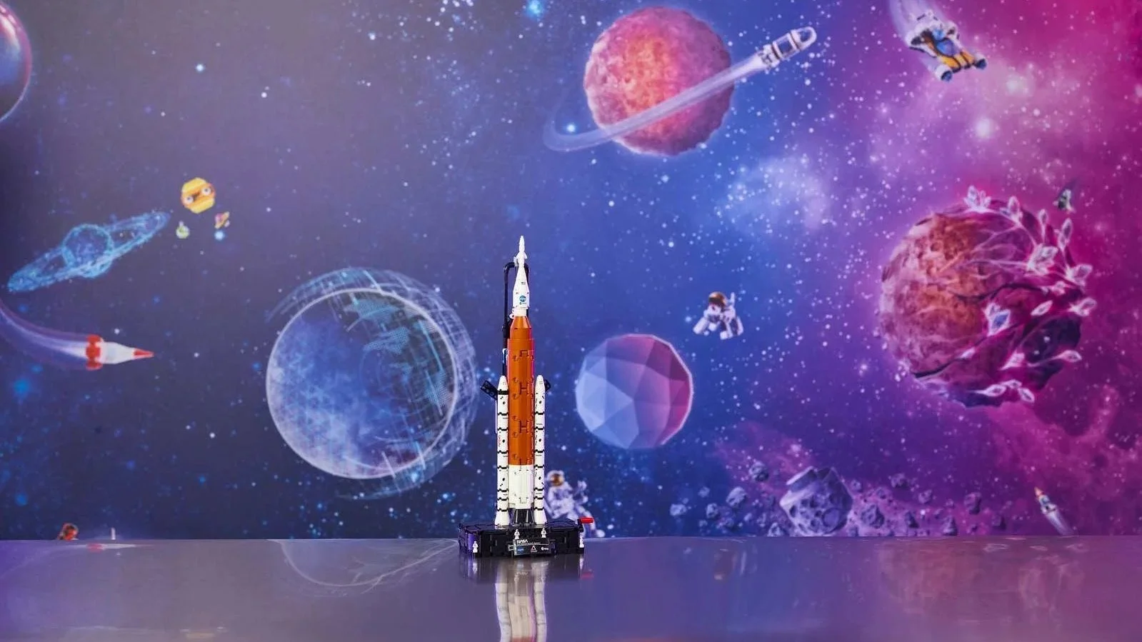 LEGO NASA Artemis Space Launch System rocket in orange and white on its launch base against a colorful galaxy backdrop