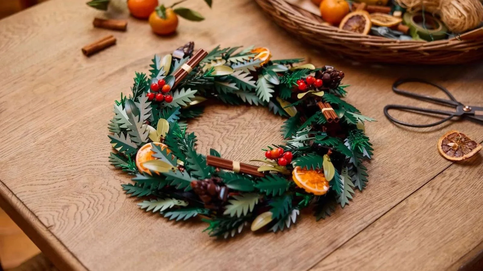 LEGO Wreath of green leaves, red berries, orange slices, cinnamon sticks, and pinecones on a wooden table