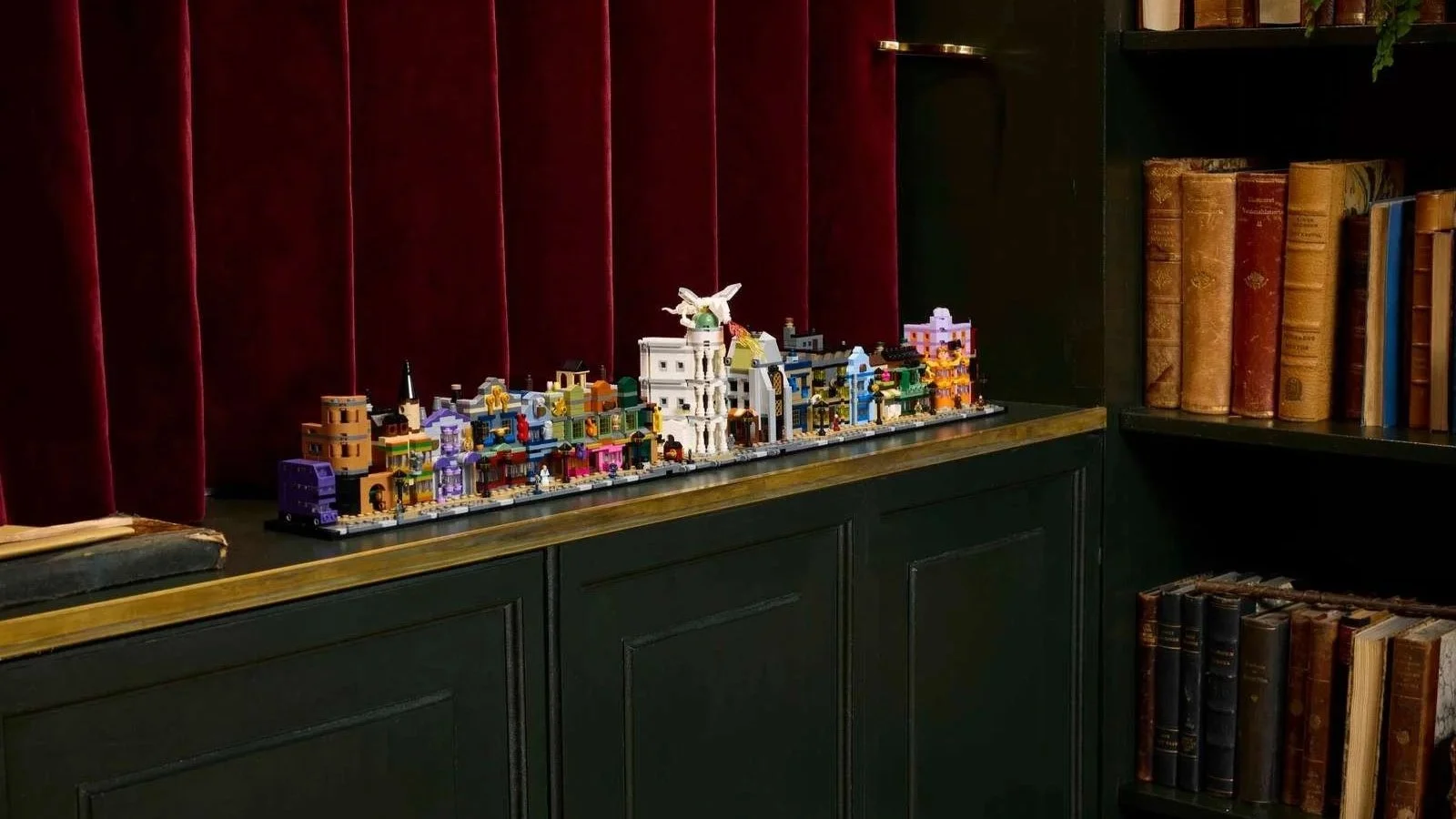 LEGO Diagon Alley Wizarding Shops set lined up along a dark green counter in front of a red velvet curtain