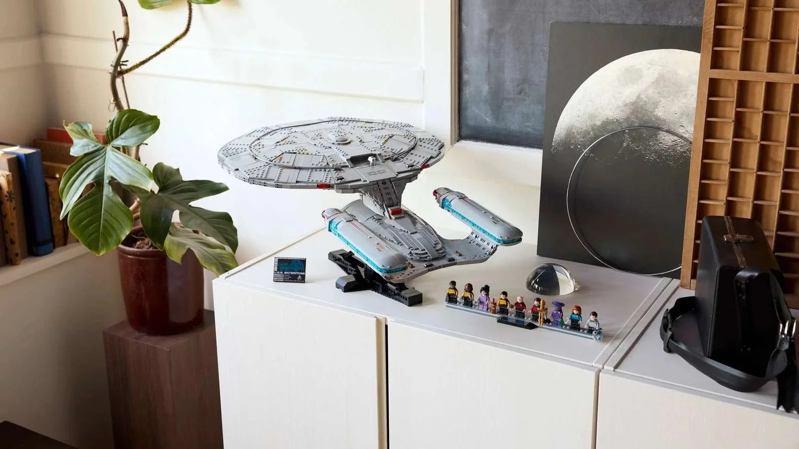LEGO Star Trek U.S.S. Enterprise NCC-1701-D set displayed on a white cabinet with its crew minifigures