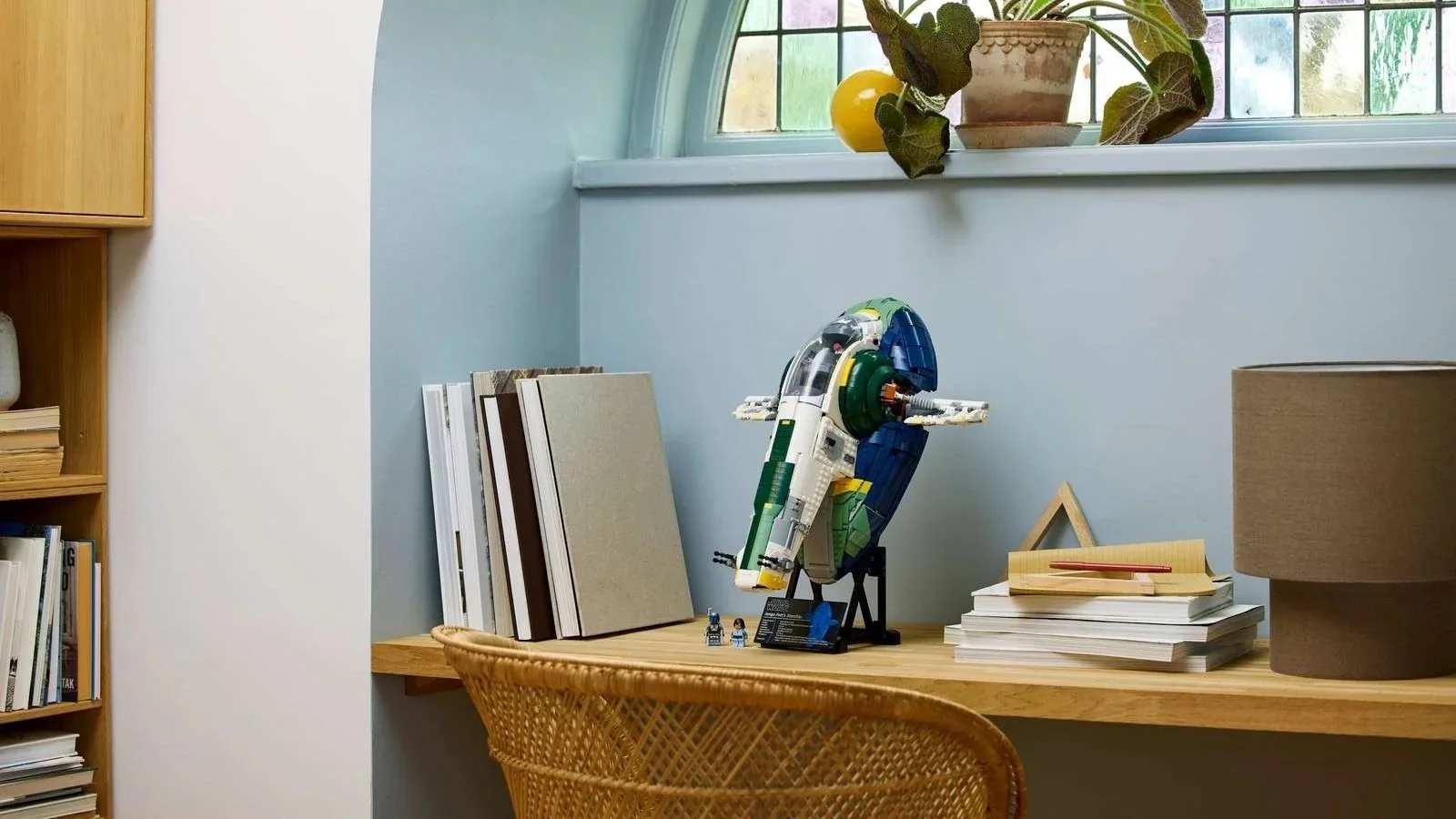 LEGO Star Wars Jango Fett's Firespray-Class Starship on its display stand on a desk under an arched window