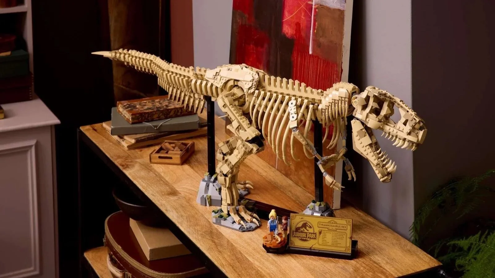 LEGO Tyrannosaurus rex fossil skeleton set posed on a wooden table, with a Jurassic Park plaque and two minifigures at its feet.