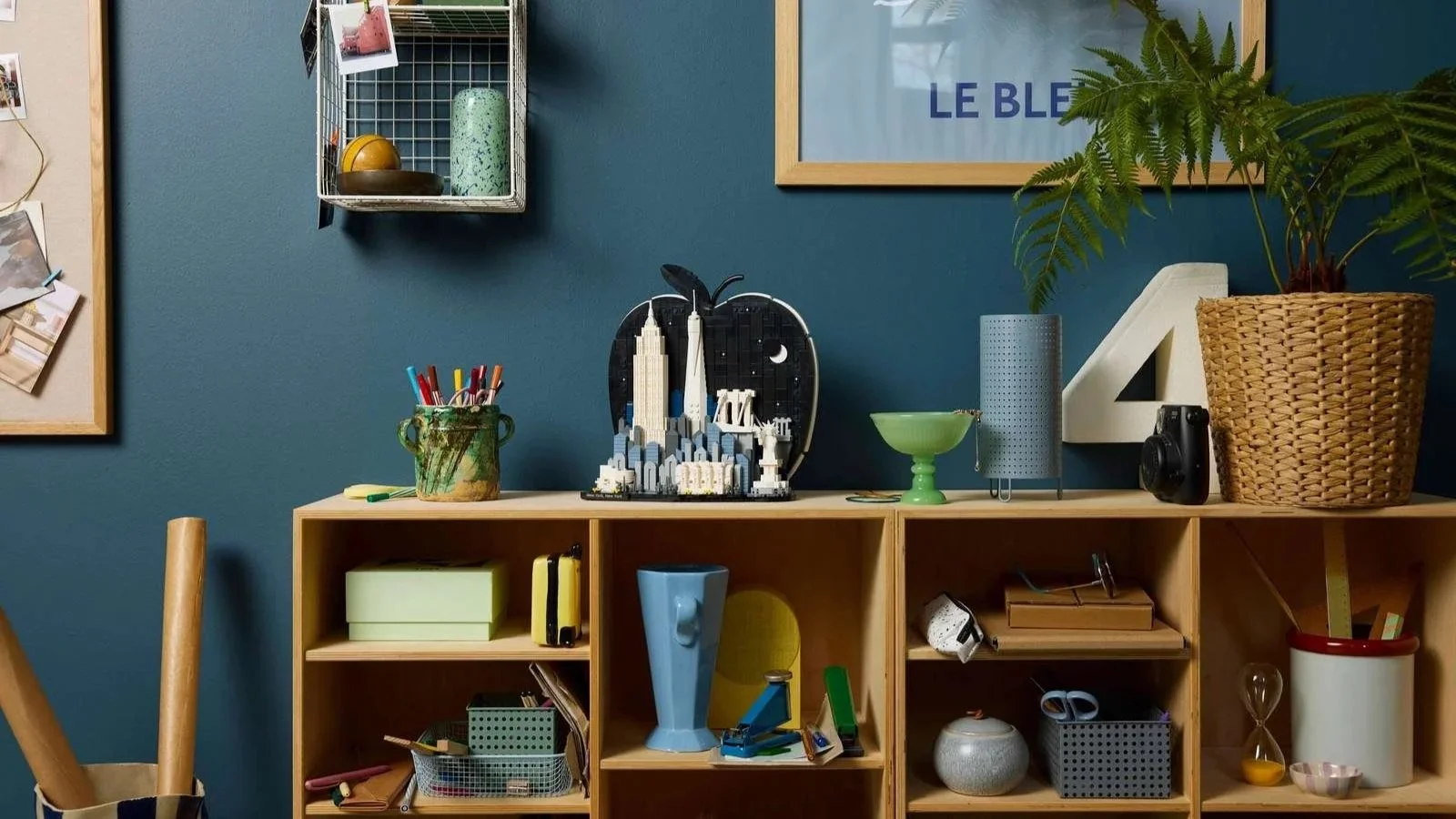 LEGO Architecture New York City set with the Statue of Liberty on a craft room shelf beside a fern and a jar of pens