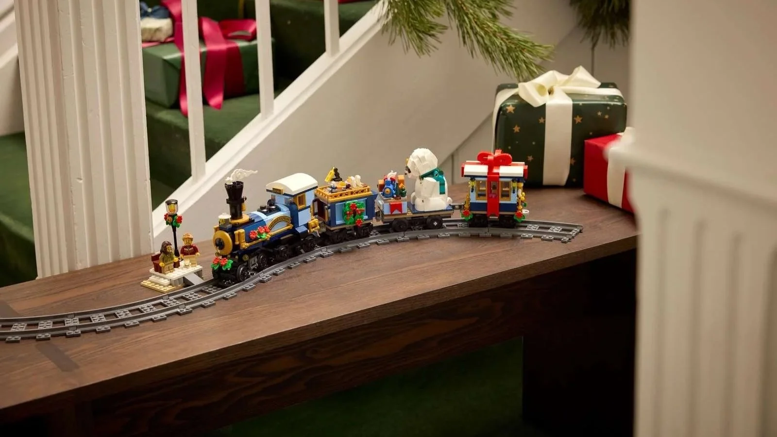 LEGO Holiday Express Train with a blue steam engine and gift-bow carriage on curved track along a wooden bench