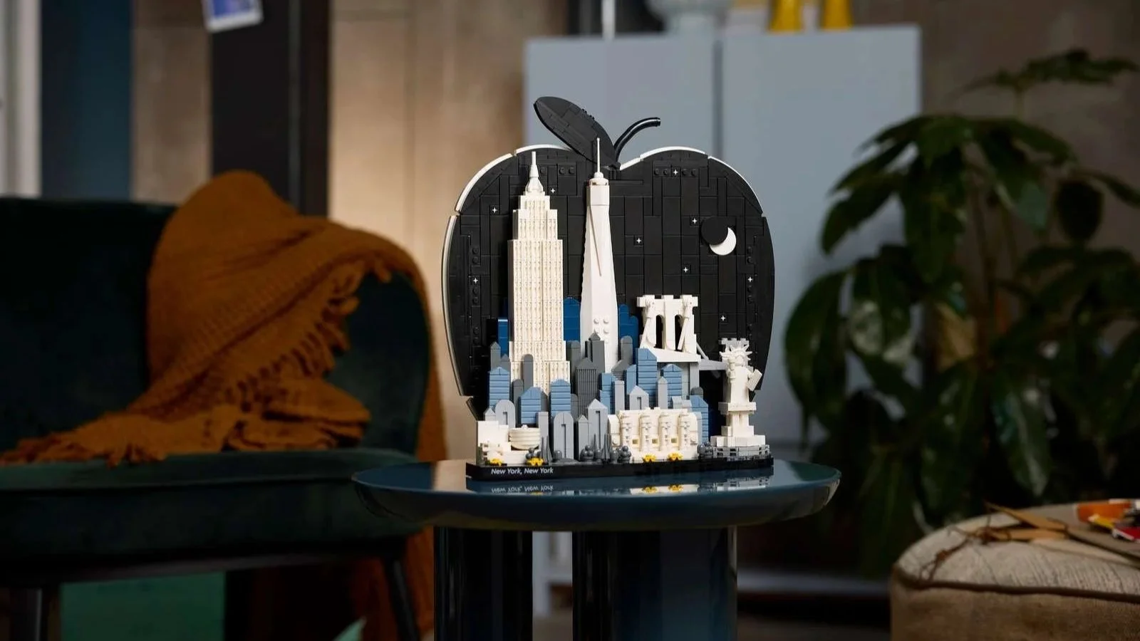 LEGO Architecture New York City set with a Big Apple silhouette on a side table beside a green velvet armchair