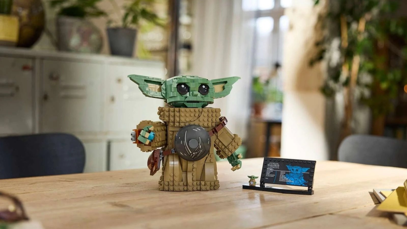 LEGO Star Wars Grogu set, a large brick-built figure with big green ears, with a display plaque and a mini Grogu on a wooden table