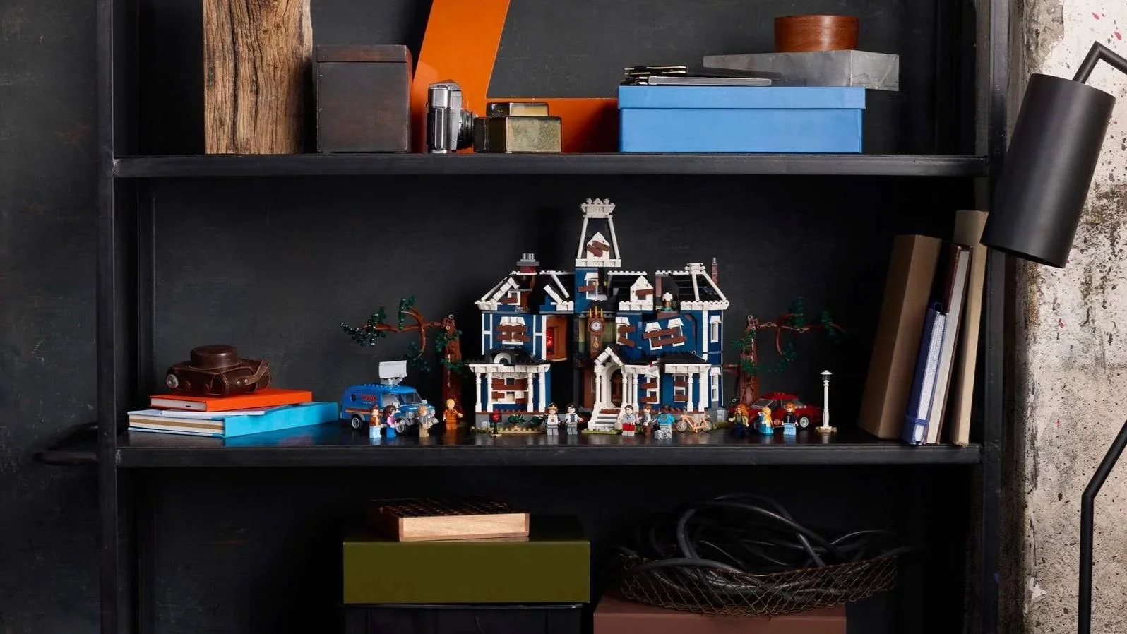 LEGO Stranger Things Creel House set with boarded-up windows and minifigures lined along a black shelf