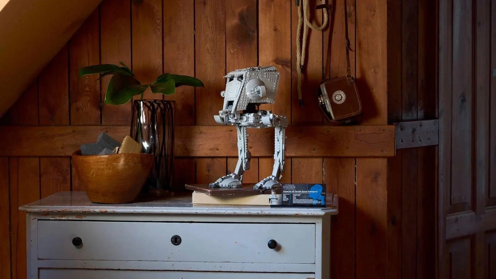 LEGO Star Wars AT-ST Walker displayed on a weathered gray dresser against a wood-paneled wall