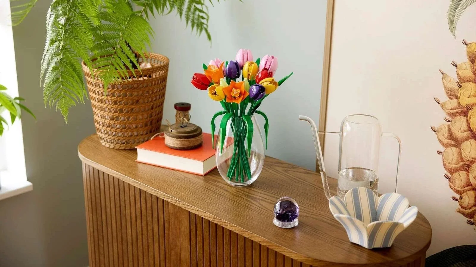 Colorful LEGO Tulip Bouquet in a clear glass vase on a wooden sideboard beside a potted fern
