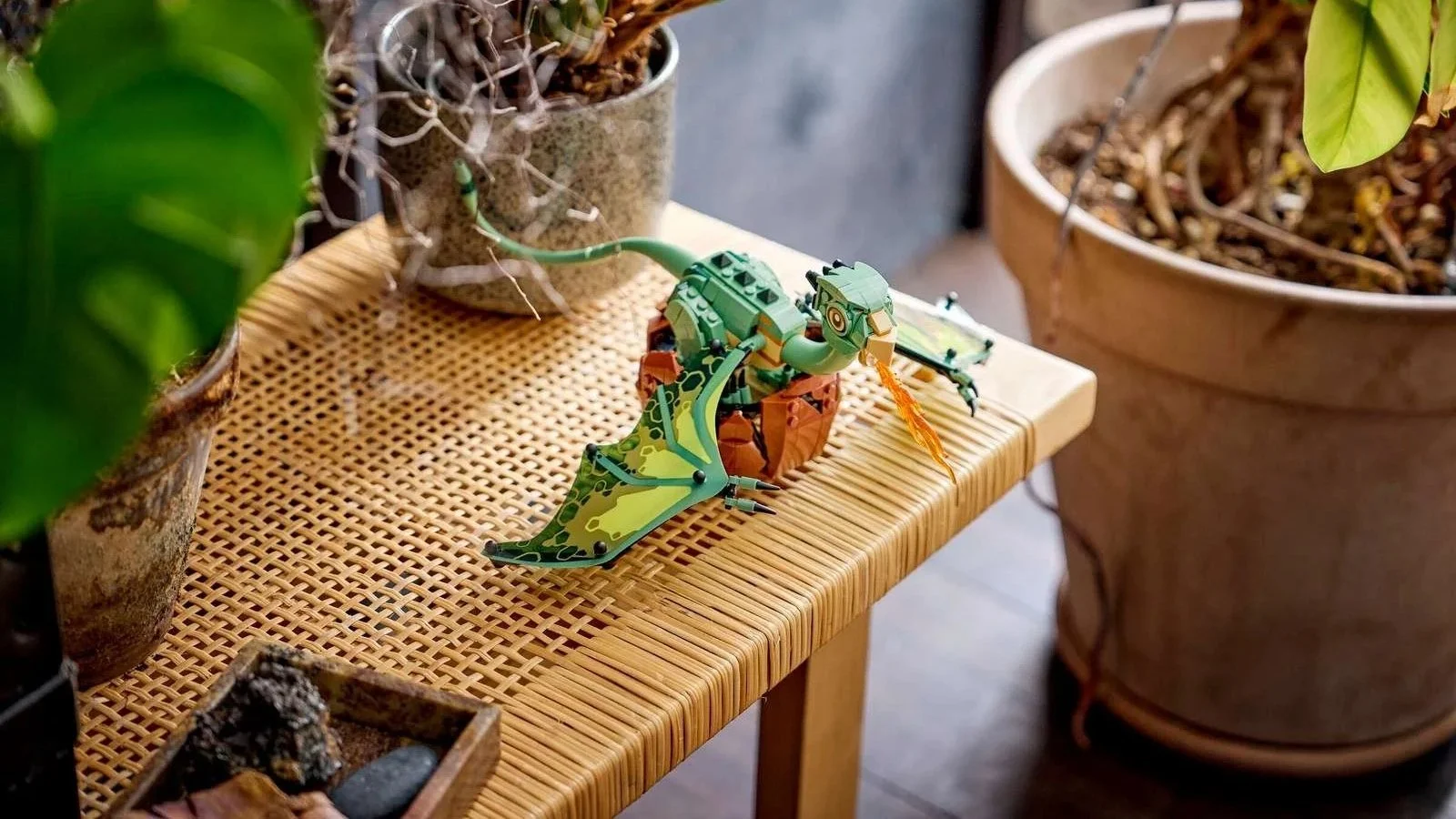LEGO Norbert: Hagrid's Baby Dragon set breathing a translucent orange flame on a rattan table among houseplants
