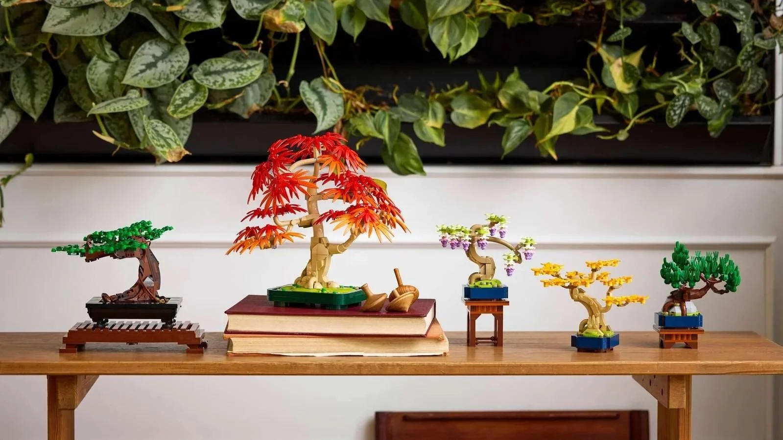 All three LEGO bonsai sets – Bonsai Tree, Japanese Red Maple, and Mini Bonsai Trees – lined up on a wooden console