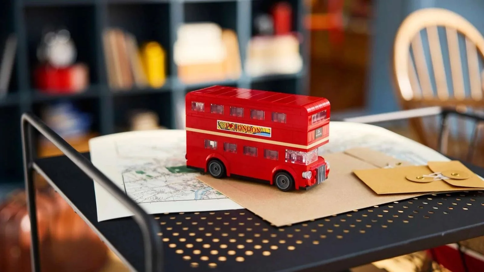 Red LEGO London double-decker bus on a city map and kraft envelope on a black metal shelf