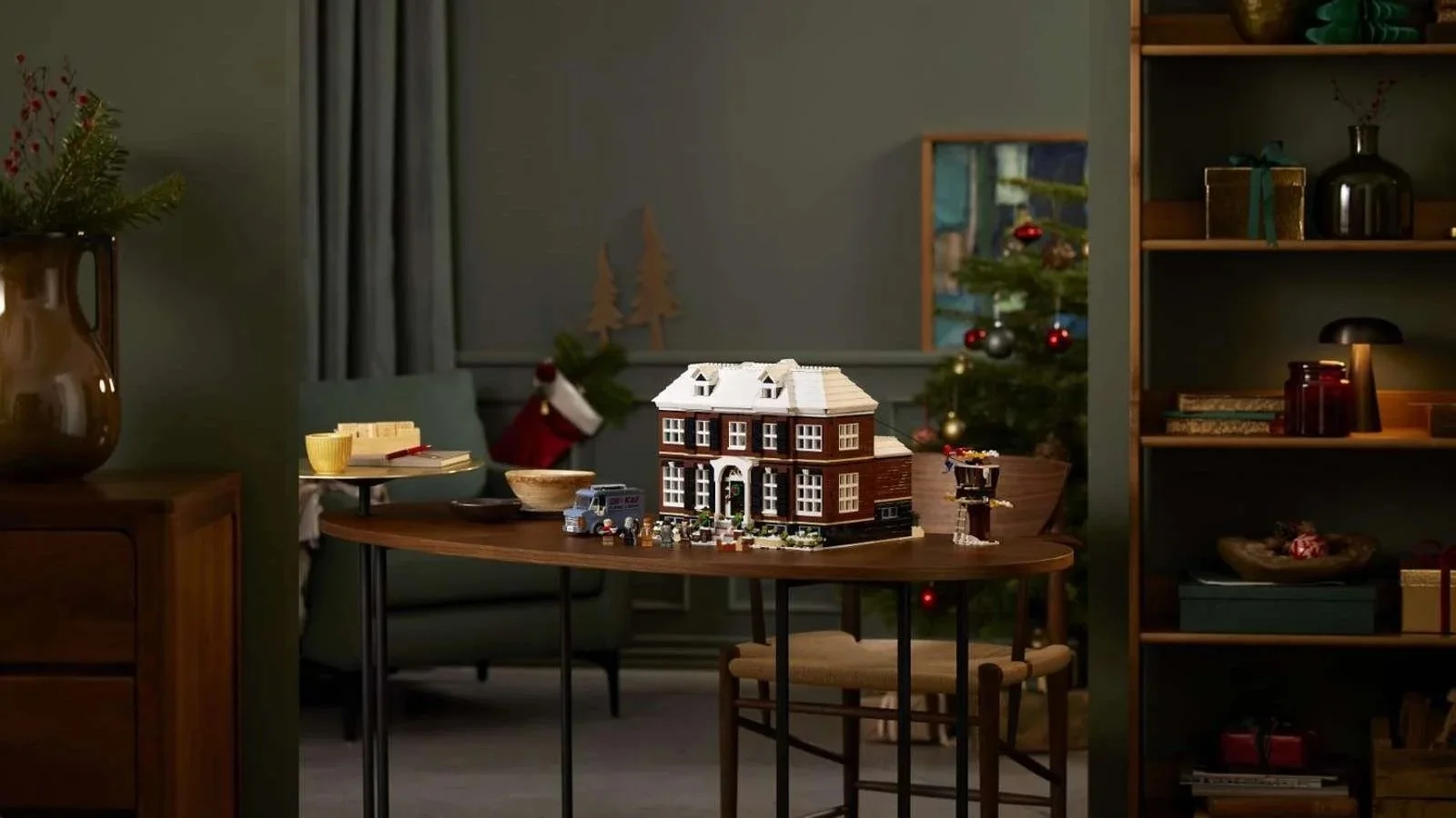 LEGO Ideas Home Alone set with the McCallister house displayed on a dining table in a living room decorated for Christmas.