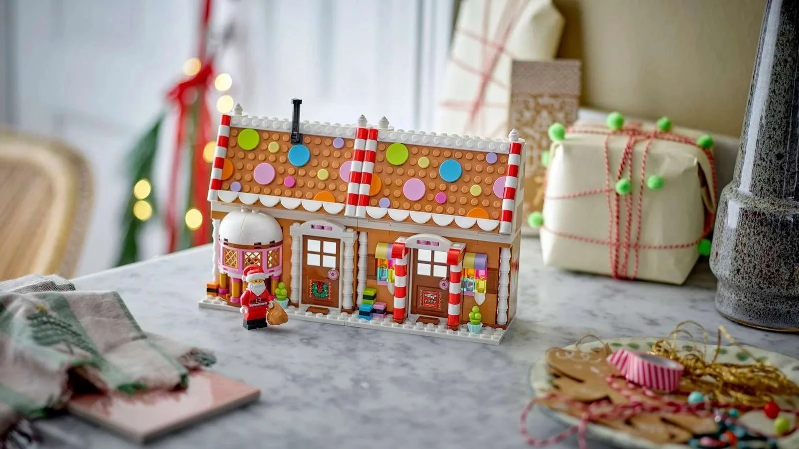 LEGO Festive Gingerbread House with a roof covered in colorful candy dots, candy cane columns and a Santa figure by the door