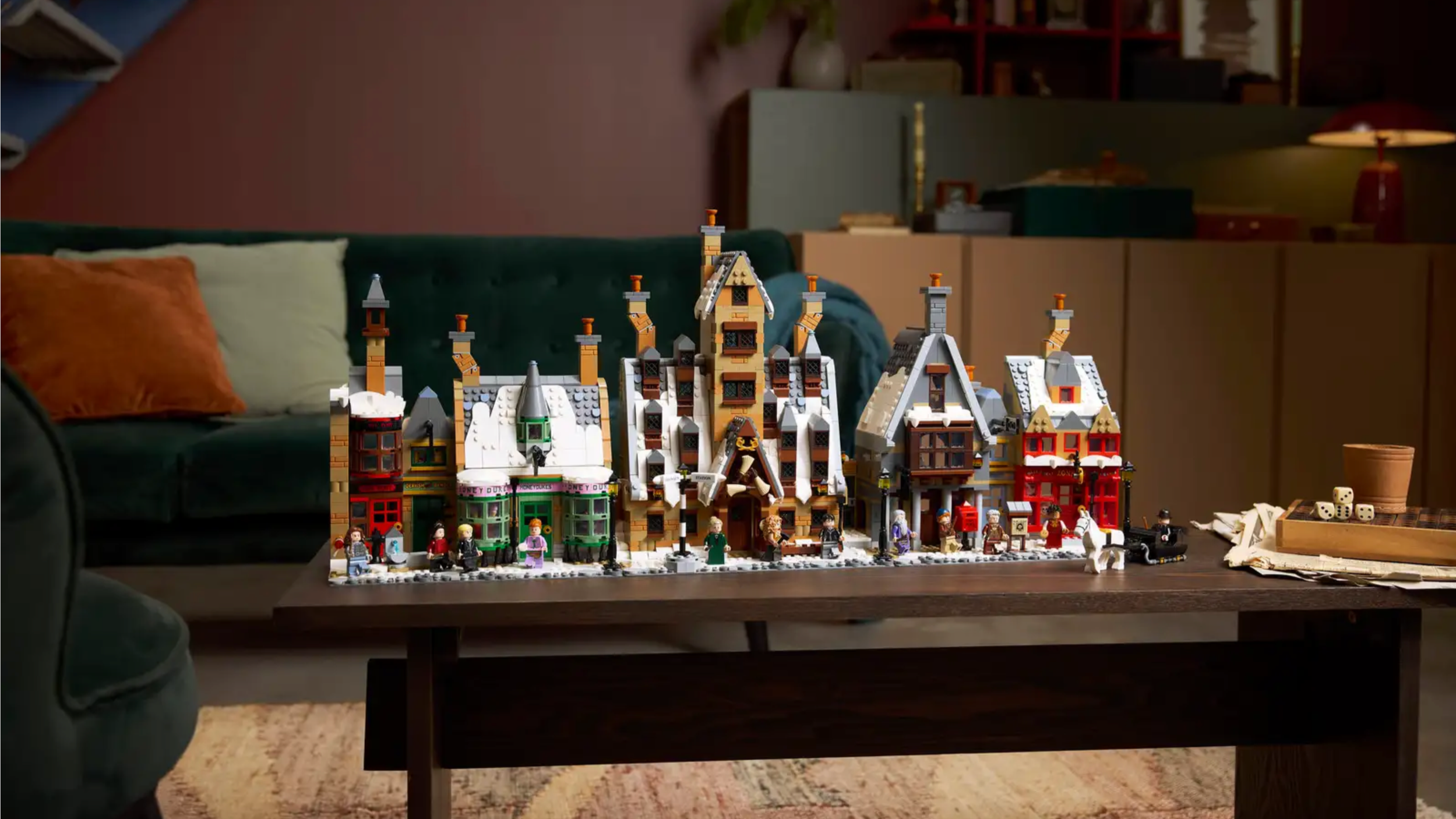 LEGO Hogsmeade Village – Collectors' Edition set with snow-covered shops on a coffee table in a cozy living room
