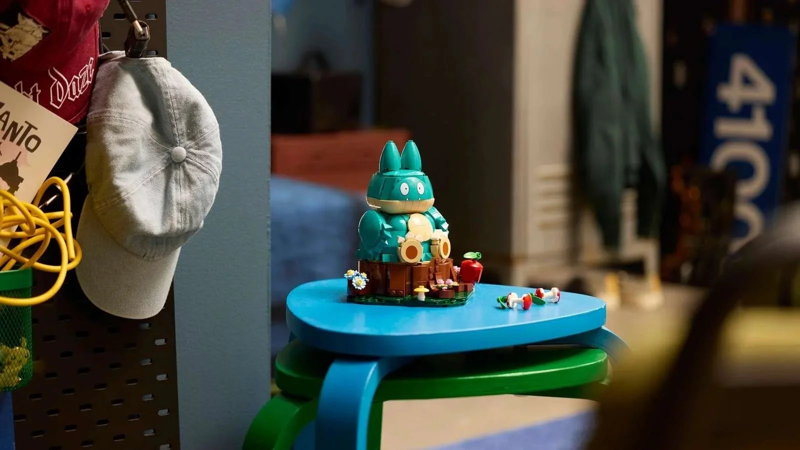 LEGO Munchlax set on a tree stump base with an apple and mushrooms, displayed on a blue stool in a casual room
