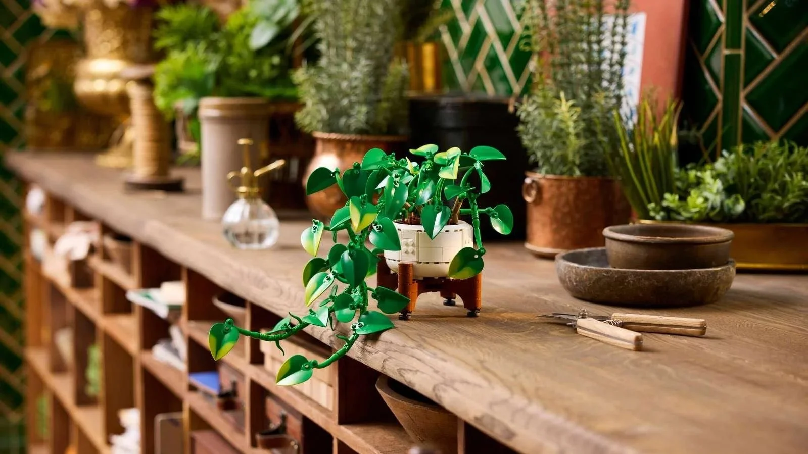 LEGO Hanging Golden Pothos plant with trailing yellow and green leaves cascading over the edge of a wood shelf surrounded by real potted plants