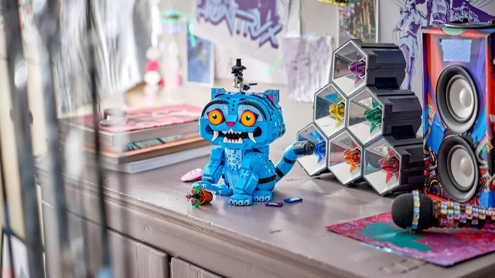 LEGO KPop Demon Hunters Derpy Tiger and Sussie Bird set on a dresser, a blue tiger with big orange eyes and fangs and a small black-hatted bird perched on its head