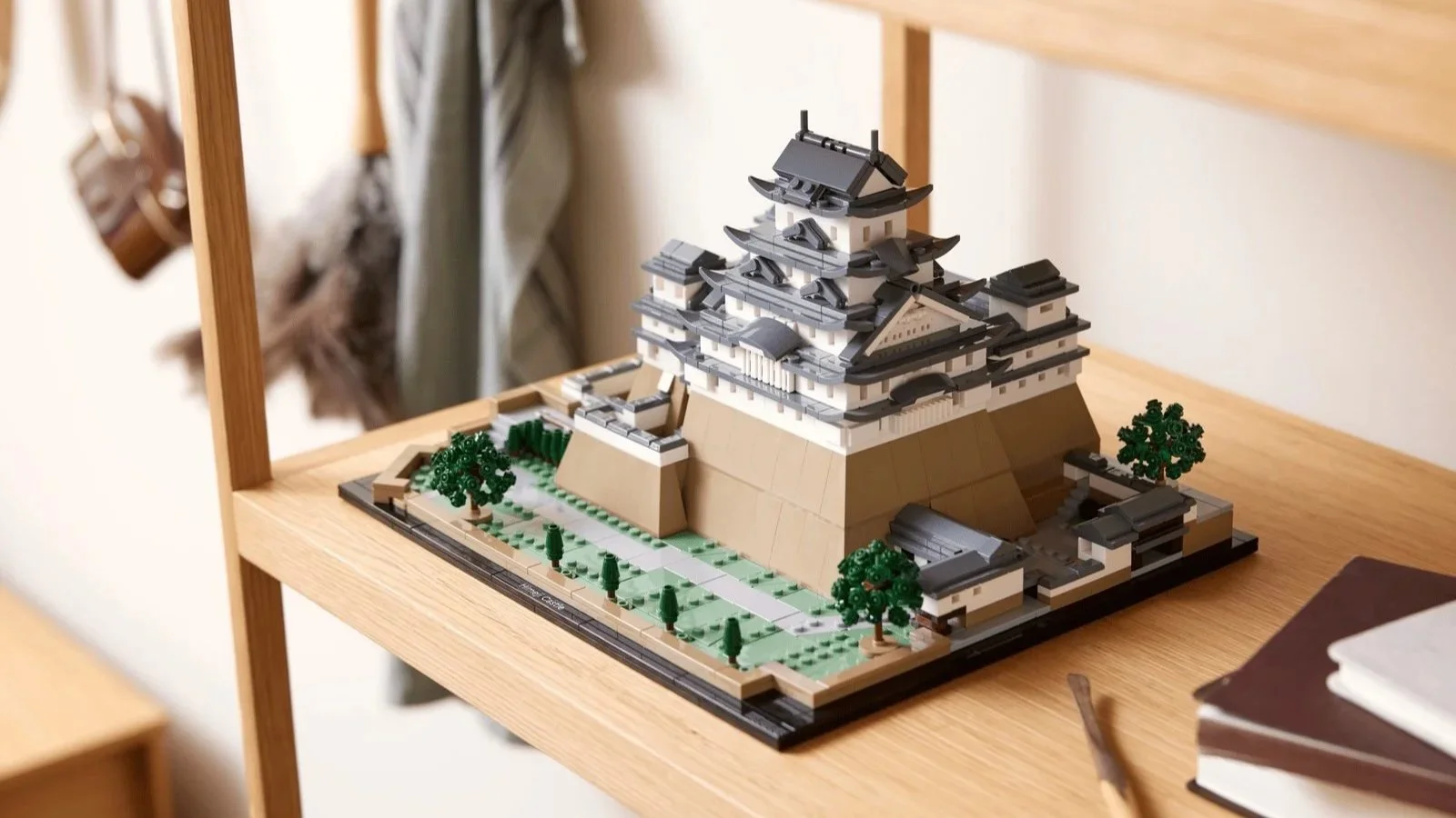 LEGO Himeji Castle set on a pale oak shelf with white walls, tiered gray roofs, and tiny green trees