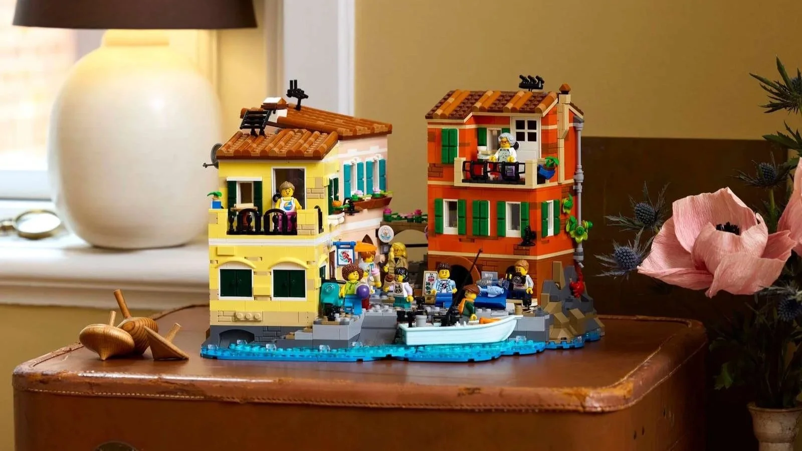LEGO Italian Riviera set displayed on a leather suitcase, with a close view of the harbor buildings, fishing boat, and minifigures