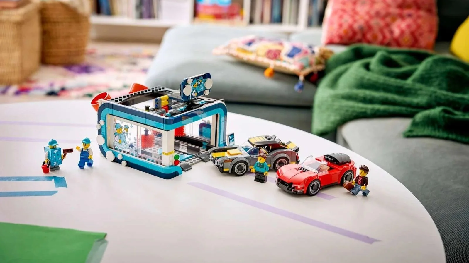 LEGO Drive-Through Car Wash set with a blue and white wash building, a gray sports car, a red convertible and minifigures on a white coffee table