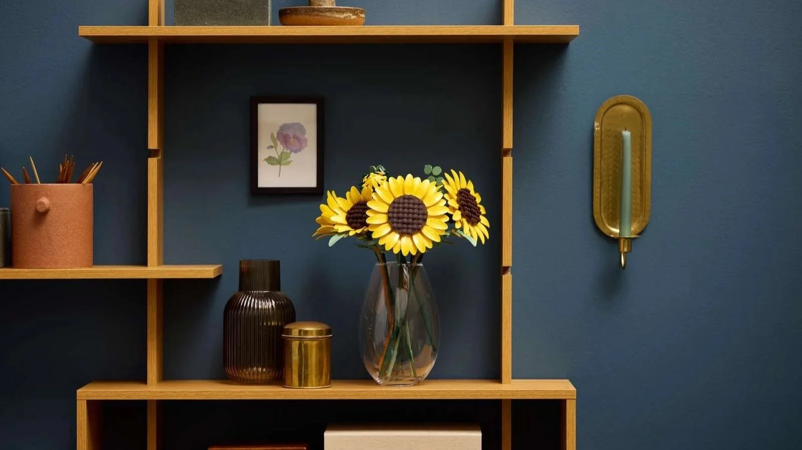 LEGO Sunflower Bouquet set in a clear glass vase on wooden shelves against a navy blue wall