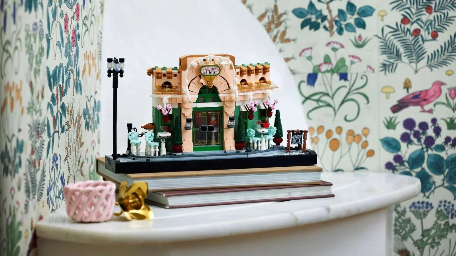 LEGO French Café set with sidewalk tables displayed on stacked books against botanical print wallpaper