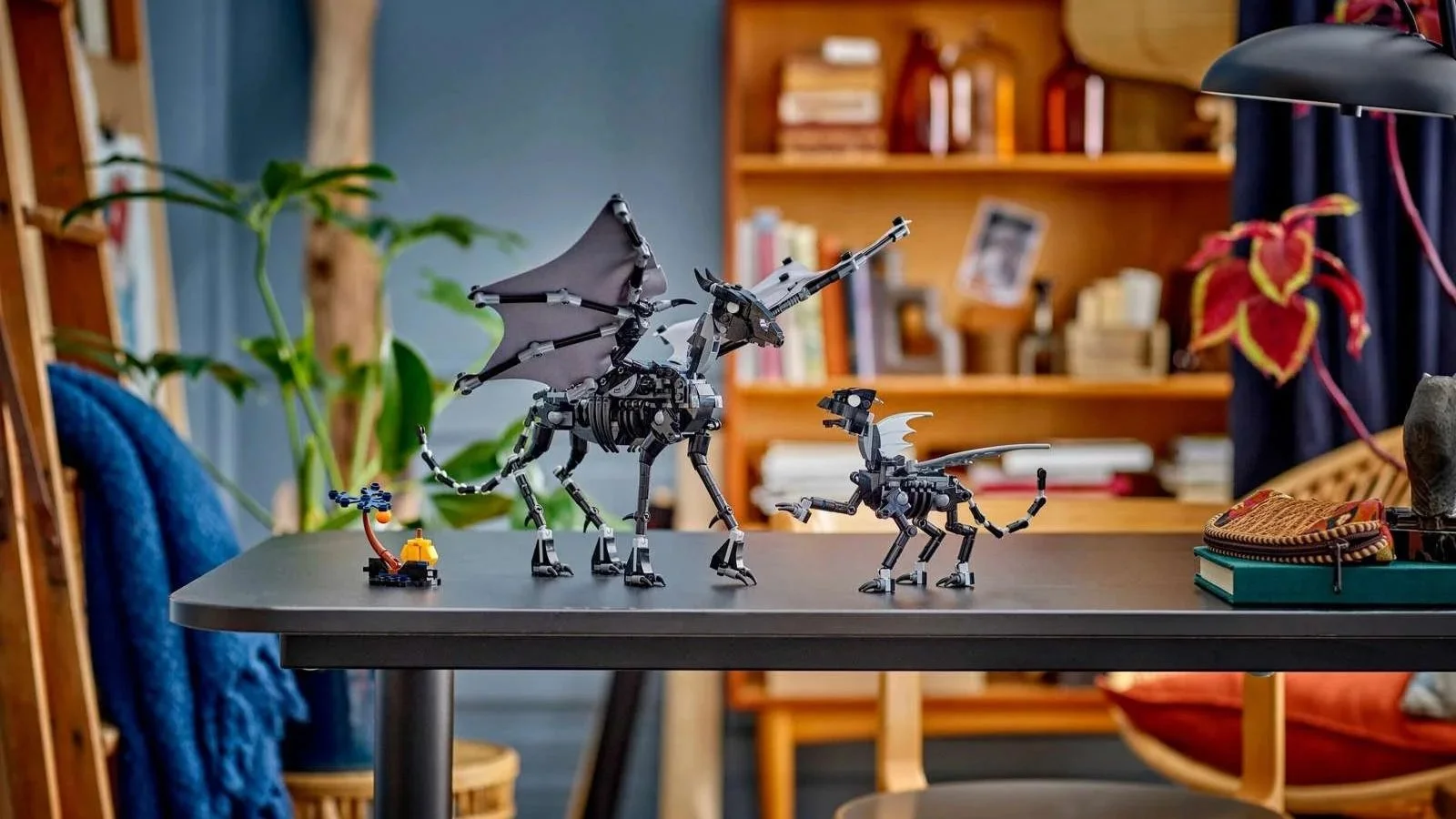 LEGO Thestral Family set with an adult and a baby skeletal winged horse and a small pumpkin, displayed on a dark desk in a cozy room
