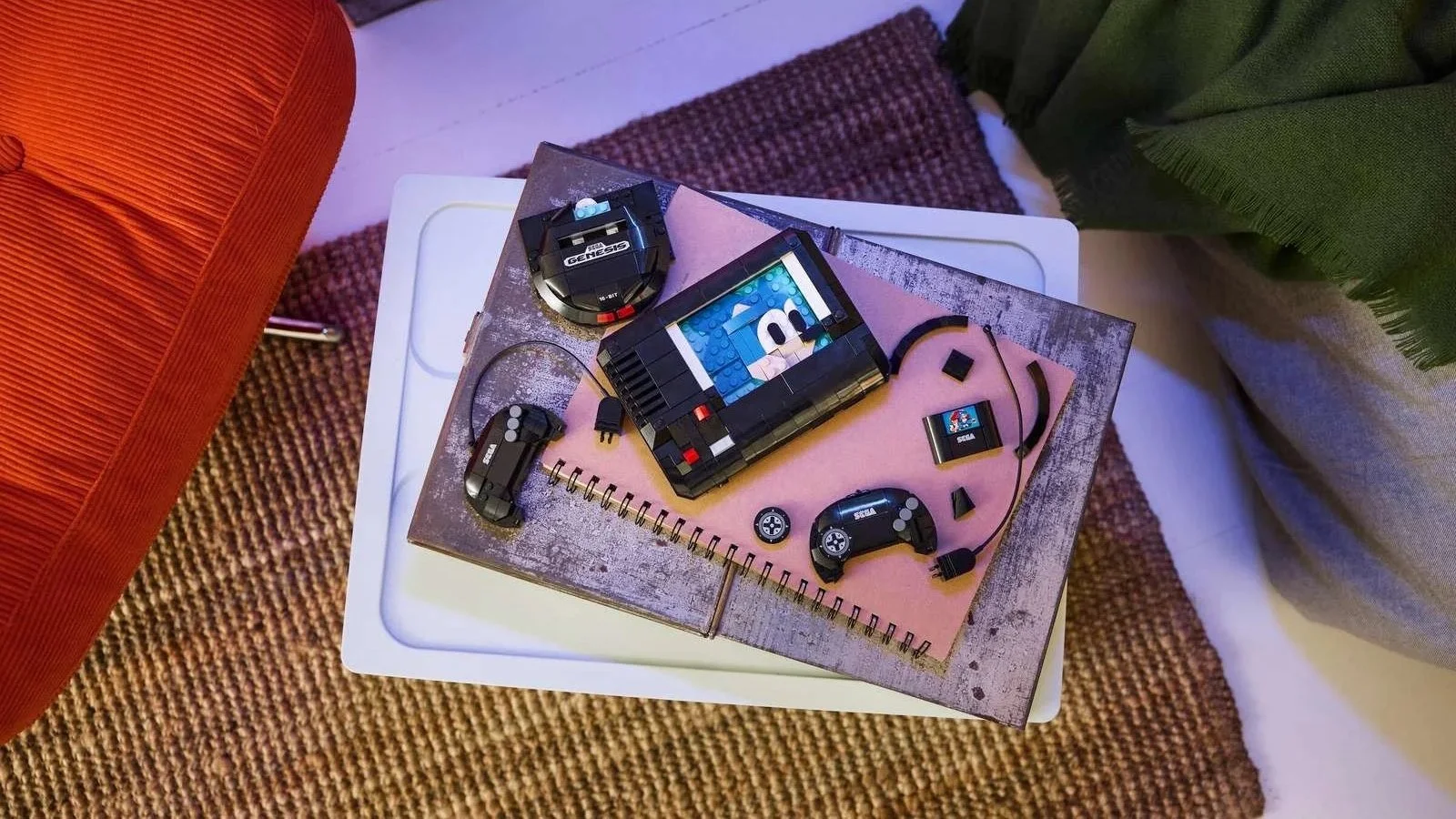 Overhead view of the LEGO SEGA Genesis console with its controllers and game cartridge arranged on a notebook
