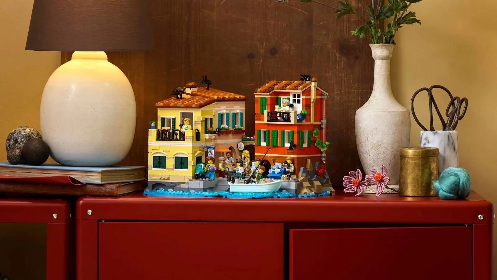 LEGO Italian Riviera set displayed on a red cabinet, showing its yellow and red waterfront buildings and harbor scene with minifigures