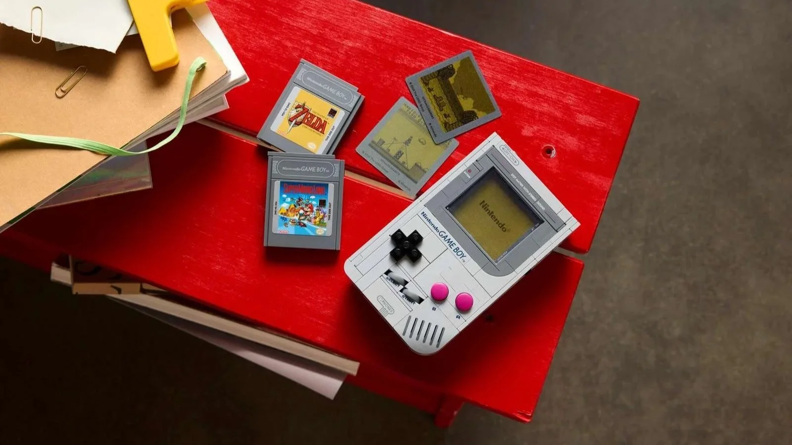 EGO Game Boy set viewed from above on a red table, surrounded by Zelda and Super Mario Land game cartridges